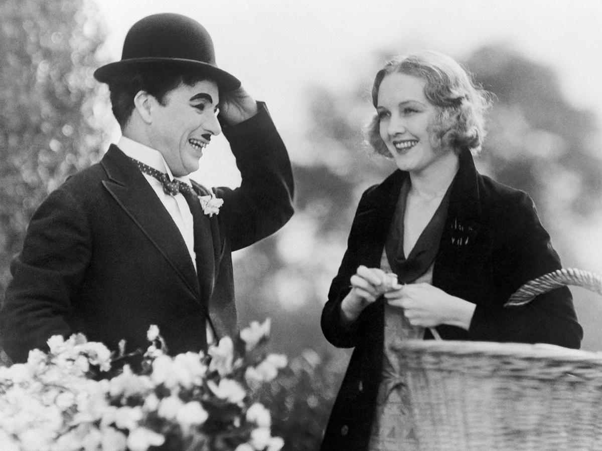 English born actor Charlie Chaplin brings a floral offering to actress Virgina Cherrill, who plays a blind girl, from a scene in the film "City Lights", Jan. 5, 1931. The film was produced by Chaplin. (AP Photo)